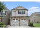 Charming townhome featuring a stone facade and two-car garage with decorative doors at 252 Stone Park Dr, Woodstock, GA 30188