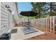 Charming patio with a black umbrella, dining set, privacy fence, and mature trees in background at 146 Sunset Ln, Woodstock, GA 30189