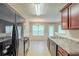 Modern kitchen with stainless appliances, sink and dishwasher, and dining area in the background at 513 Shadow Valley Ct, Lithonia, GA 30058