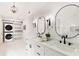 Well-lit bathroom featuring dual vanities, quartz counters, black fixtures, and laundry machines at 3795 Newport Bay Dr, Alpharetta, GA 30005
