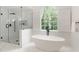 Modern bathroom with a spacious glass shower and freestanding tub under a large window at 3795 Newport Bay Dr, Alpharetta, GA 30005