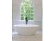 Serene bathroom with a modern soaking tub beneath a large arched window with green views at 3795 Newport Bay Dr, Alpharetta, GA 30005