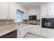 Well-lit kitchen with white cabinetry, a built-in microwave, and sleek black appliances for a modern cooking experience at 1105 Buckhurst Dr, Atlanta, GA 30349