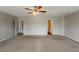 A large bedroom featuring neutral walls, carpet, a ceiling fan, and two open doors at 440 Pinevale Ct, Atlanta, GA 30349