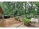 A view of a tiered back deck with flower plantings, a table, and a barbecue area surrounded by lush greenery at 3229 Richwood Dr, Duluth, GA 30096