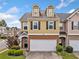 Charming townhome featuring yellow siding, dormer windows, a brick foundation, and a two-car garage at 44 Providence Oak Ct, Lawrenceville, GA 30046