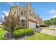 Front view of a tan and brick townhome with a two-car garage and manicured landscaping at 44 Providence Oak Ct, Lawrenceville, GA 30046