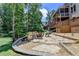 Backyard with stone patio, outdoor seating, fire pit and steps leading to the home's porch at 5245 Cottage Farm Rd, Johns Creek, GA 30022