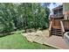 Stone patio with fire pit, landscaped backyard, and stairs to the upper-level screened-in porch at 5245 Cottage Farm Rd, Johns Creek, GA 30022