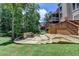 Backyard view featuring a stone patio with fire pit, stairs to an upper porch, and wooded perimeter at 5245 Cottage Farm Rd, Johns Creek, GA 30022