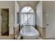Bathroom boasts a tub under an arched window, a glass shower, and white vanity at 5245 Cottage Farm Rd, Johns Creek, GA 30022