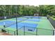 Aerial view of well-maintained tennis courts surrounded by lush greenery and fencing at 5245 Cottage Farm Rd, Johns Creek, GA 30022