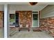 Welcoming covered porch with brick accents, cushioned bench, and decorative wreath creates cozy entrance at 595 Glenforest Rd, Sandy Springs, GA 30328