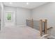 Upstairs hallway with neutral carpet, wooden railing with black iron spindles, and view of bedrooms at 908 Catamaran Ct, Alpharetta, GA 30005