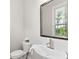 Bright powder room featuring pedestal sink, decorative mirror, and hardwood floors at 908 Catamaran Ct, Alpharetta, GA 30005