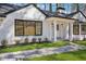 White brick home featuring black window frames, a covered porch with white pillars, and attractive landscaping at 335 Amberidge Nw Trl, Atlanta, GA 30328