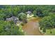 Aerial shot featuring two houses near a pond with a fountain, surrounded by dense, mature trees at 11180 West Rd, Roswell, GA 30075