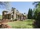 Expansive backyard with lush green lawn, mature trees, a stone patio, and a charming seating area at 11180 West Rd, Roswell, GA 30075