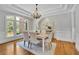 Charming dining room with wainscoting, a tray ceiling, a chandelier, and large windows overlooking the yard at 11180 West Rd, Roswell, GA 30075