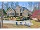 Inviting stone and brick home featuring a landscaped front yard with a multi-car driveway and beautiful trees at 11180 West Rd, Roswell, GA 30075