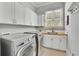 Well-lit laundry room with modern washer and dryer, plus ample cabinet space at 11180 West Rd, Roswell, GA 30075