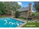 Back exterior of home featuring a private pool surrounded by stone pavers and lush landscaping at 11180 West Rd, Roswell, GA 30075