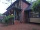 View of a red brick home featuring an outdoor porch with gray pillars and stairs at 5741 Wolf Laurel Ln, Lilburn, GA 30047