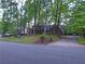 View of a red brick two-story home with manicured front yard surrounded by mature trees and bushes at 5741 Wolf Laurel Ln, Lilburn, GA 30047