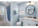 A well-lit powder room featuring tile floors, a sink and vanity, mirror, and a shower with blue curtain at 2350 Rosebrook Se Xing, Atlanta, GA 30339