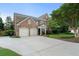 Elegant brick home with a well-manicured lawn, a two-car garage, and mature trees on a sunny day at 2350 Rosebrook Se Xing, Atlanta, GA 30339