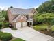 Aerial view of a two-story brick home with a spacious driveway, two-car garage, and lush landscaping at 2350 Rosebrook Se Xing, Atlanta, GA 30339