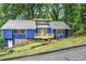Charming blue home featuring a stone foundation, a welcoming front porch, and lush green landscaping at 468 Watson Ferry Dr, Forest Park, GA 30297