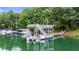 Modern dock with boat lift on a green lake surrounded by dense trees, perfect for lakeside living at 6178 Lake Lanier Height Rd, Buford, GA 30518
