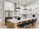 Open kitchen featuring a large island with seating, stainless steel appliances, and modern light fixtures at 6178 Lake Lanier Height Rd, Buford, GA 30518