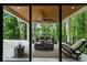 View from inside overlooking the covered patio with wicker furniture and wooded views at 6178 Lake Lanier Height Rd, Buford, GA 30518