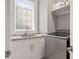 Laundry room featuring granite countertops, white cabinets, stainless steel appliances, and a window at 717 Lenox Ln, Atlanta, GA 30324