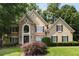 Charming front elevation of tan home with stone accents, black trim, and professionally landscaped yard at 820 Chelsea Park Ne Dr, Marietta, GA 30068