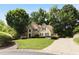 Two-story tan home with stone accents, mature trees, and driveway on professionally landscaped lawn at 820 Chelsea Park Ne Dr, Marietta, GA 30068