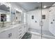 Modern bathroom with double vanity, white cabinets, glass enclosed shower with pebble floor, and tiled walls at 11352 Musette Cir, Alpharetta, GA 30009