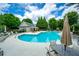 Community pool area with lounge chairs, tables, and lush landscaping on a sunny day at 11352 Musette Cir, Alpharetta, GA 30009