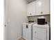 A well-lit laundry room features a washer, dryer, and white cabinets at 146 Silver Leaf Trce, Douglasville, GA 30134