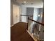 Well-lit hallway with brown carpet, a wooden banister, and a light fixture at 1498 Park Knoll Trl, Lawrenceville, GA 30043