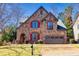 Charming stone home with red shutters, arched entryway, and a well-manicured front lawn at 4595 Carriage Walk Ln, Cumming, GA 30040