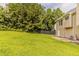 Spacious backyard featuring green grass, bordered by trees, and siding of the home at 1006 Eagle Vw, Lawrenceville, GA 30044