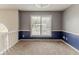 Spacious carpeted room featuring blue and gray walls, wainscotting, and a window with a neighborhood view at 1006 Eagle Vw, Lawrenceville, GA 30044