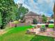 Spacious backyard with a stone patio, outdoor fireplace, dining set, and green grass at 2458 Brook Park Trl, Snellville, GA 30078