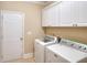 Bright laundry room featuring white cabinets, washer, and dryer at 2458 Brook Park Trl, Snellville, GA 30078