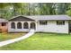 Charming brick home with gray accents, beautiful yard, black shutters, and a sidewalk leading up to the front porch at 3530 Turner Heights Dr, Decatur, GA 30032