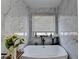 Bright bathroom featuring a soaking tub with a decorative window and luxurious marble tiling at 2410 Melton Common Dr, Dacula, GA 30019