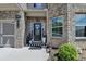 Close-up of a home's front entrance with a wreath on the door and plants flanking the entrance at 2410 Melton Common Dr, Dacula, GA 30019